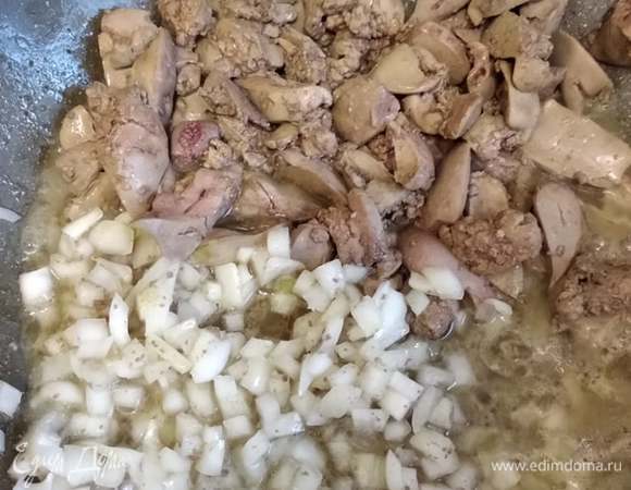 На ту же сковороду, слегка подвинув печень, выложить лук и обжарить еще 1–2 минуты. Посолить, поперчить, приправить майораном. Посыпать мукой и перемешать.