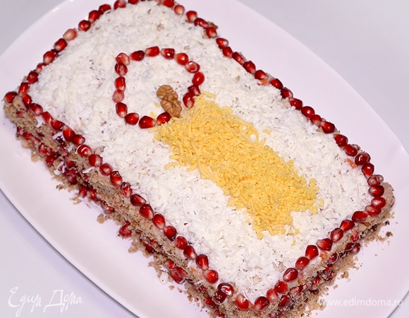 Посыпаю салат отварным белком, пропущенным через мелкую терку, чтобы структура поверхности была однородной и походила на полотно или фон. Украшаю бока смесью из гранатовых зернышек и молотых грецких орехов. Этот процесс похож на украшение тортов бисквитной крошкой. Для свечи понадобится желток, натертый на мелкой терке, опять же немного грецких орехов или часть ореха и гранатовые зернышки, чтобы нарисовать пламя. Всем приятного аппетита и счастливого Рождества! :)