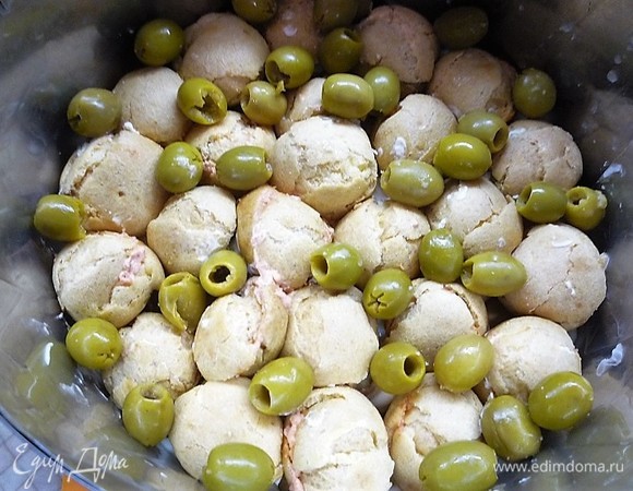 Погружаем все профитроли в мусс, между ними выкладываем маслины.