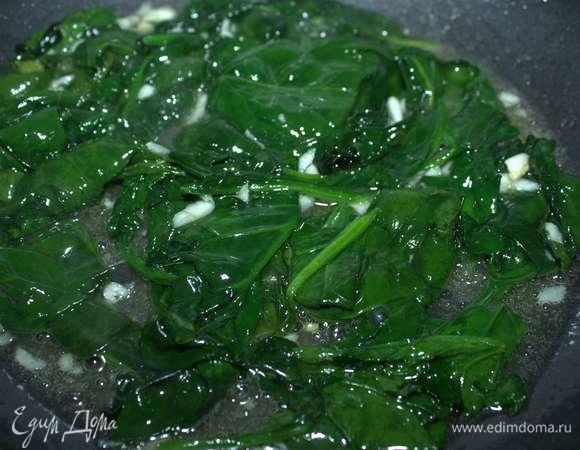 Тем временем шпинат обжарим на растительном масле около двух минут, добавляем кусочки чеснока и обжариваем еще около одной минуты.