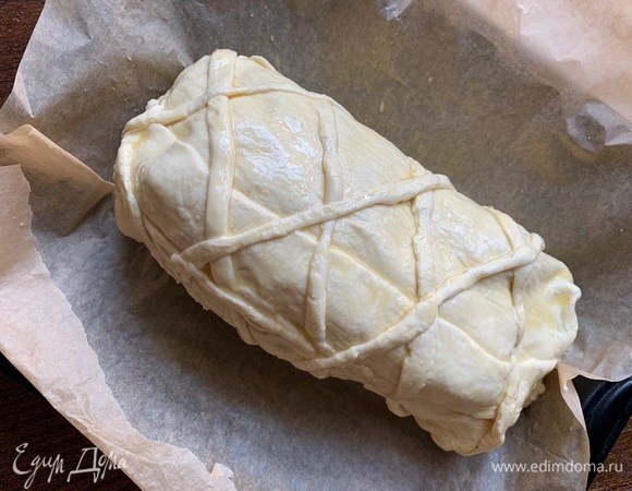 Форму выложить пергаментом. Духовку разогреть до 190°C. Тесто смазать желтком. Выпекать минут 20–25.