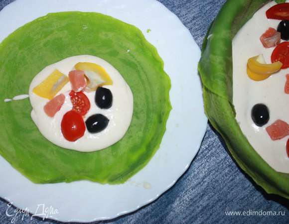 На отдельную тарелку выкладываем блин, сверху — крем и заполняем блинчик всеми ингредиентами начинки (рыбой, помидорами, маслинами и сладким перцем).