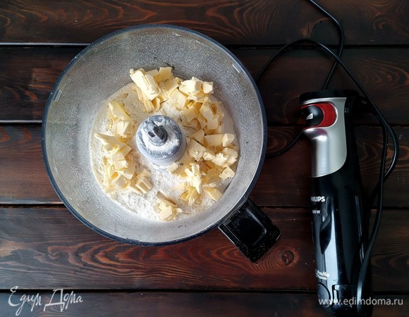 Если у вас есть кухонная машина, то в дежу миксера помещаем муку и ледяное сливочное масло. Смешиваем насадкой весло на минимальной скорости до получения крошки. Нет кухонной машины — берем и делаем то же самое в блендере, только на большой скорости.