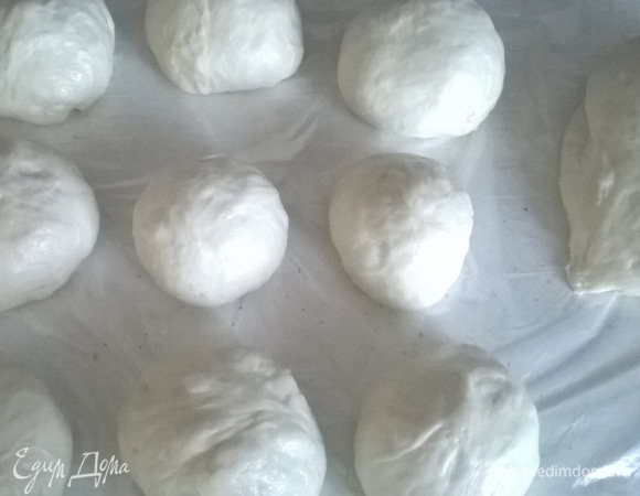 Подошедшее тесто разделываем на небольшие части и делаем из них шарики, которые затем разминаем и скручиваем рулетиком. Так наши готовые булочки не будут слишком толстенькими и круглыми, потому как в процессе выпекания они сильно увеличатся. Перекладываем на противень и даем подойти.