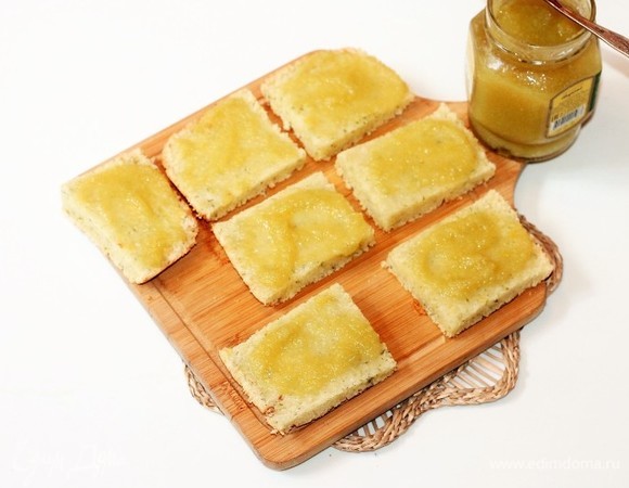 Полностью остывшие квадратики разрезаем на 2 части и смазываем джемом. Выкладываем пирожные на блюдо и посыпаем кокосовой стружкой.