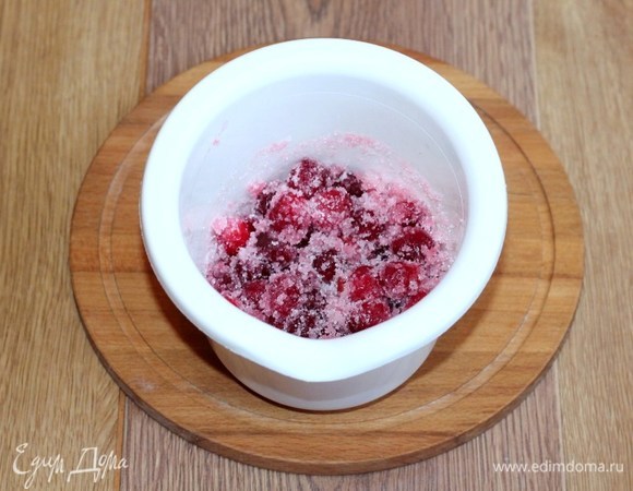 Замороженную клюкву промываем проточной водой. Затем выкладываем клюкву в чашу блендера, добавляем сахар и измельчаем до однородной консистенции.