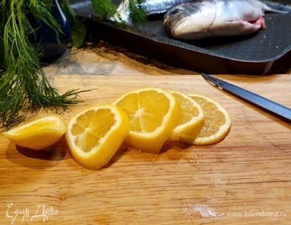 Теперь самый нужный ингредиент — лимон. Нарезаем и закладываем в рыбу.