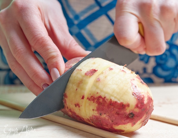 Нарежьте картофелины тонкими дольками не до конца. Очень удобно для этого пользоваться бамбуковыми палочками, как ограничителями.