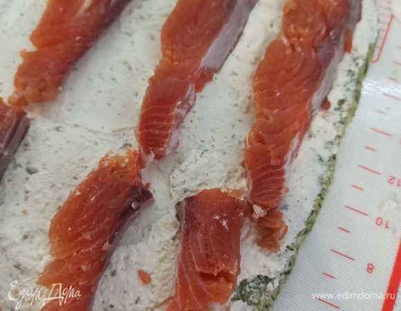 Сверху выкладываем рыбку. И сворачиваем плотно в рулет. Заворачиваем в пищевую пленку и убираем на 3 часа в холодильник, чтобы рулет прописался и немного застыл. Нарезаем порционными кусочками и подаем к столу!