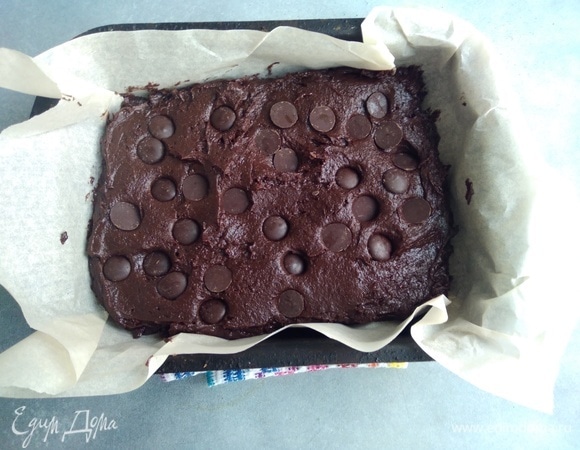 Духовку разогреть до 180°C. Форму выстелить пергаментом, распределить тесто по форме, сверху добавить шоколадные капли. Поставить в духовку на 20–25 минут.