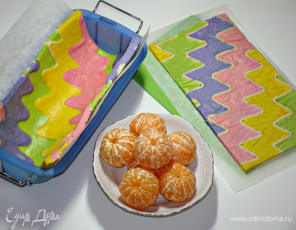 Форму выстлать пекарской бумагой и уложить бисквит. Мандарины очистить от кожуры.