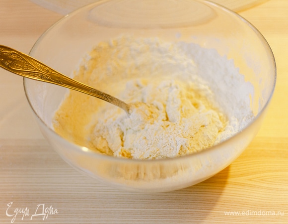 Добавить половину муки и перемешать. Затем добавить вторую половину и замесить тесто.