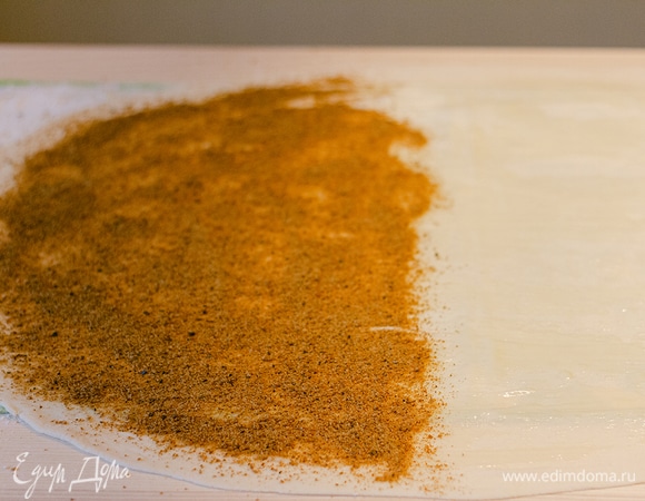 Смазать весь пласт теста растопленным сливочным маслом. Затем на половину насыпать панировочные сухари.