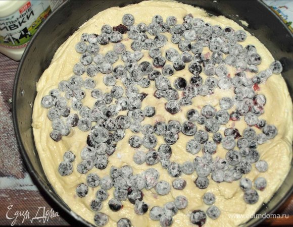 У меня разъемная форма диаметром 27 см. Форму смазать растительным маслом. Выкладываем в подготовленную форму тесто. Равномерно распределяем по форме. Замороженную черную смородину размораживать не надо. Смородину соединить с крахмалом. Выкладываем смородину сверху на тесто.