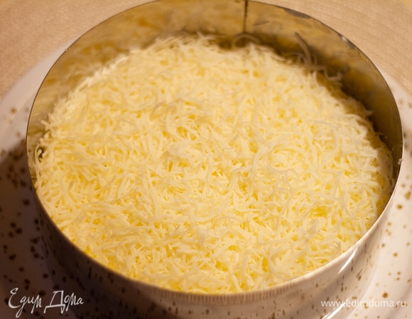 Натереть на терке яйца, выложить четвертым слоем и смазать майонезом. Затем пятый слой — посыпать сверху натертый сыр.