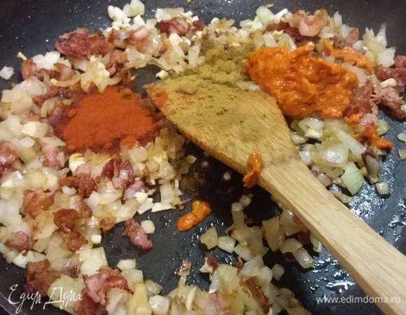 Итак, копченую свинину залить 1,5 литрами воды и варить 20 минут. В это время разогреть в сковороде масло и обжарить бекон до золотистого цвета, добавить лук и пассеровать до прозрачности. Добавить чеснок, порошок красной паприки, зиру и пасту из перцев (у меня айвар — это тоже паста из запеченных перцев). В оригинальном рецепте на этом этапе советуют добавить 70 г муки, я обошлась без нее. Обжарить все вместе и выложить смесь в кастрюлю с супом.