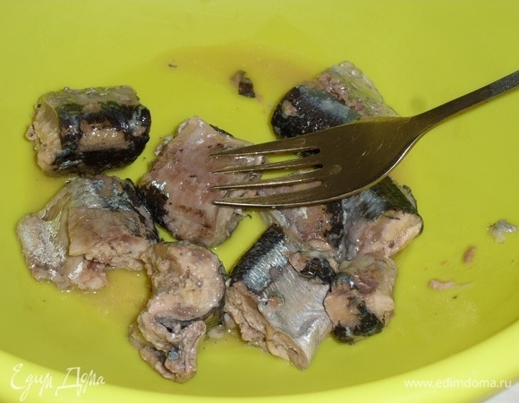 В глубокую чашку выкладываем куски консервированной рыбы (сайра, скумбрия, сардина и так далее). Слегка разминаем вилкой.