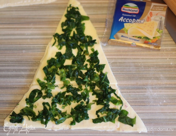 Треугольник, у которого есть шов, будет нижним. Выкладываем на него пластинки сыра или, если нет пластинок, можно посыпать тертым сыром, сверху — мелко нарезанный шпинат. Шпинат можно перед этим измельчить.