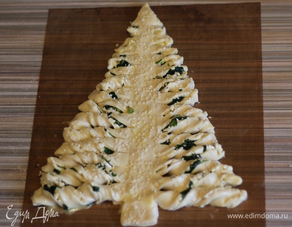 Каждую полосочку аккуратно скручиваем несколько раз спиралькой. Смазываем желтком, посыпаем кунжутом и отправляем в духовку на 20–25 минут. Смотрите по своей духовке, они у всех разные: кому-то может понадобиться больше времени, кому-то поменьше. «Елка» должна получиться румяной и хрустящей.