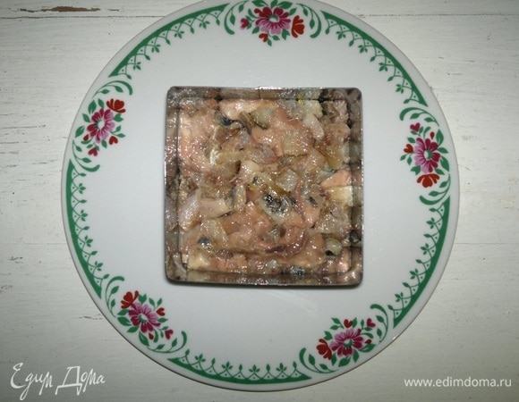 На блюдо поставить салатную форму, выложить половину сельди.