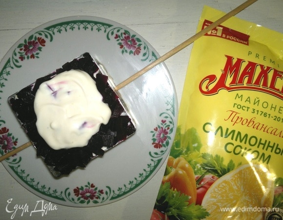 Следующий слой — половина вареной свеклы. У меня немного не хватило объема формы, и я снизу подставила под форму палочки с двух сторон. На свеклу выложить часть заправки.