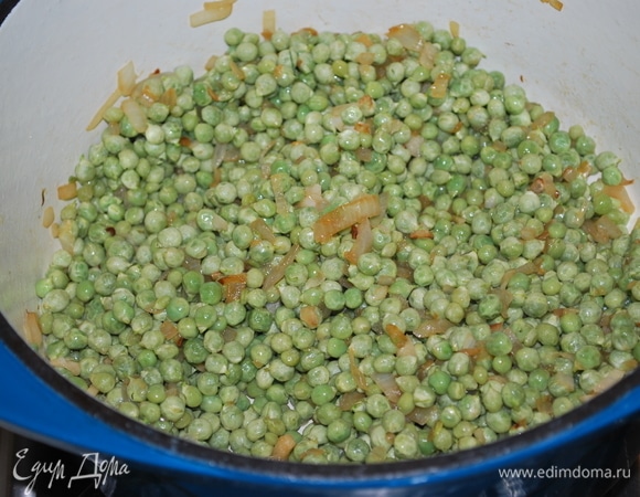 К обжаренному луку добавьте зеленый горошек (у меня замороженный горошек) и обжаривайте все вместе 2–3 минуты.