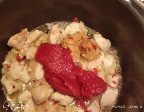 Переложить смесь лука, чеснока, перца и имбиря в кастрюлю с мясом, добавить томатную и арахисовую пасту. Перемешать и тушить 2–3 минуты.