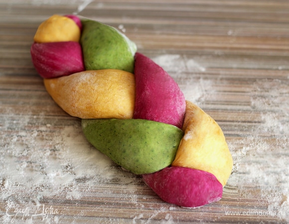 Три жгута разного цвета соедините и заплетите в косичку, концы подоткните. Плетенки выложите на противень, дайте подойти 30 минут под пищевой пленкой или влажным полотенцем. Разогрейте духовку до 180°C. Перед выпечкой аккуратно увлажните поверхность хлеба при помощи кисточки, смоченной в воде. Посыпьте хлеб кунжутом. Выпекайте 20–35 минут. Как всегда, время выпечки регулируйте по своей духовке — у всех они разные.