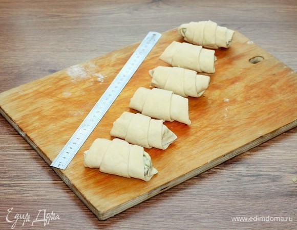 Завернуть треугольник теста с начинкой в виде рогалика. Из 2 пластин теста (500 г) у меня получилось 12 рогаликов. Застилаем противень бумагой для выпечки и смазываем растительным маслом.