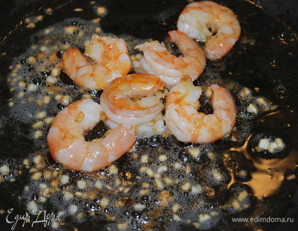Креветки почистите от панциря и черной кишки. В сковороде разогрейте оливковое масло и добавьте мелко нарезанный чеснок и креветки. Обжаривайте примерно 2–3 минуты до готовности.