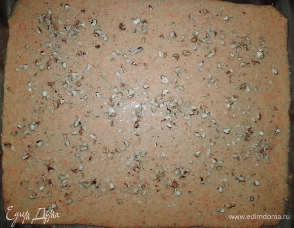 Противень застелить пергаментом, вылить тесто и равномерно распределить, сверху посыпать рублеными грецкими орешками.
