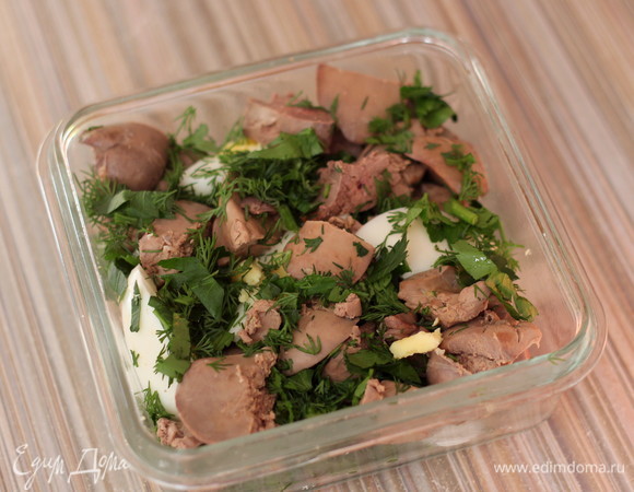 Сварить вкурутую 3 яйца, нарезать крупными кусочками. Форму для выпекания смазать сливочным маслом. Выложить в форму в хаотичном порядке кусочки печени, яйца и зелень.