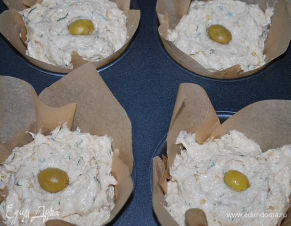 Выложите тесто в подготовленную форму (я выпекала эти маффины в больших формах). В центр выложите оливку и посыпьте семечками. Выпекайте в разогретой духовке при 170°C 45–50 минут до готовности.