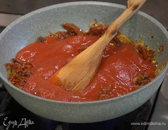 К луку выложить чеснок, вяленые помидоры, перемешать и прогревать пару минут, всыпать семена фенхеля, кайенский перец и перемешать, влить пассату и еще раз все перемешать.