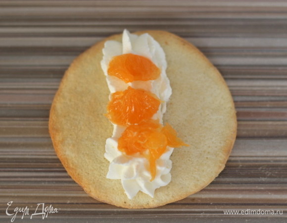 В середину кружка выкладываем немного крема, сверху — кусочки ягод или фруктов. Сгибаем края кружка к центру, немного прижимаем с боков, чтобы получилось что-то типа лодочки. Сверху закрываем кремом и украшаем.