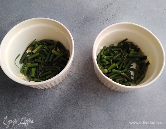 Керамические формочки или специальные кокотницы смазать сливочным маслом. На дно выложить стрелки, посолить.