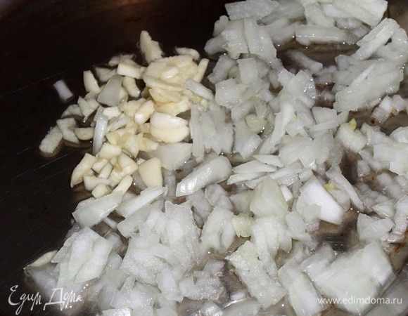 В разогретую сковороду наливаем растительное масло. Выкладываем нарезанные лук и чеснок. Перемешиваем. Обжариваем 2–3 минуты.