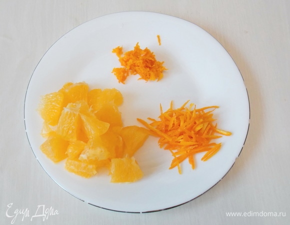 Для начала включим духовку на температуру 180°C и подготовим апельсиновую часть. Большой апельсин тщательно вымоем со щеткой в горячей воде. С одной половины снимем цедру и нарежем тонкой соломкой. Цедру с другой половины натрем на мелкой терке. Очистим апельсин от оставшейся кожуры, пленок, семян и нарежем на кусочки.