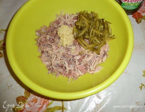 В глубокую чашку выкладываем нарезанное мясо и огурцы. Добавляем измельченный чеснок.