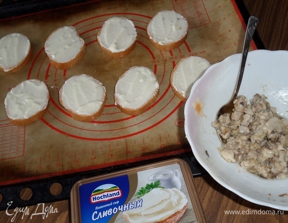 Багет нарезаем на кусочки толщиной примерно 1 см. На каждый кусочек багета выкладываем сливочный сыр и равномерно распределяем. Выкладываем кусочки багета на противень, застеленный пергаментом или силиконовым ковриком.