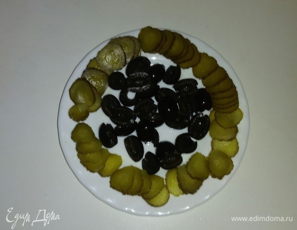 Малосольные огурцы режем тонкими кружочками. Маслины режем пополам.