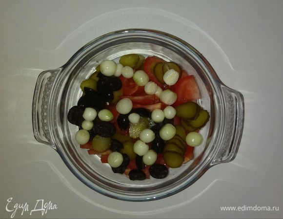 В глубокую емкость кладем нарезанные помидоры, маслины, малосольные огурцы и головки лука-севка. Если вы используете обычный репчатый лук, то нарежьте его кубиками. Перемешиваем.