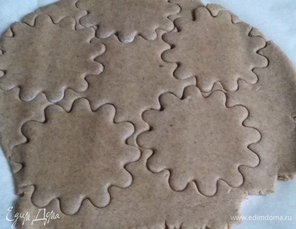 Раскатать тесто в пласт толщиной около 0,5 см. Удобнее это делать под пергаментом. Формочкой или ножом нарезать коржики.