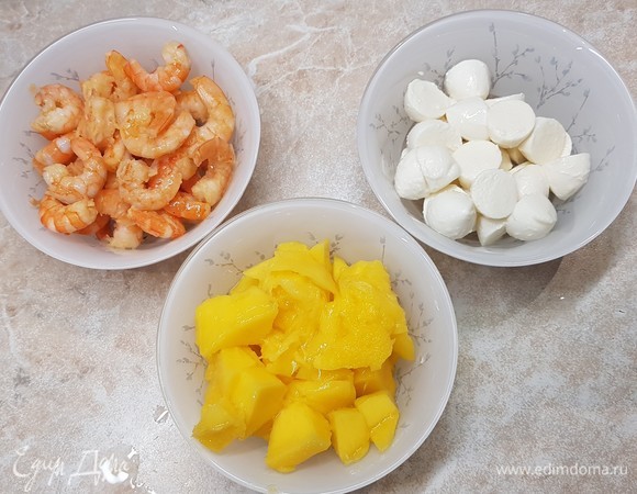 Манго очистить от кожицы и нарезать кубиками. Моцареллу мини разрезать на половинки. Креветки разморозить и обжарить на масле с чесноком 2–3 минуты.