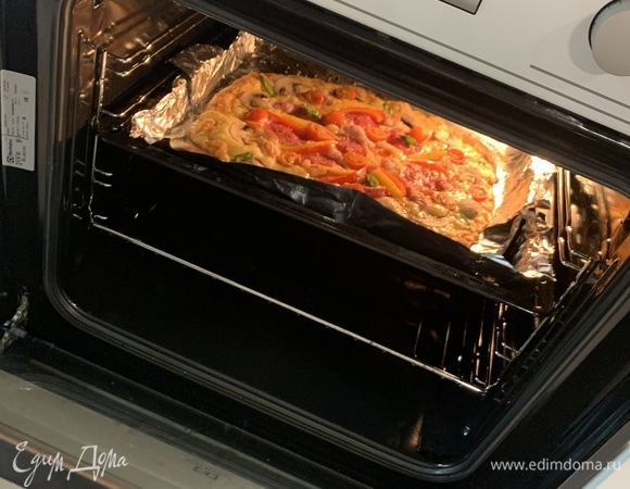 Отправляем пиццу в духовку. Выпекала первые 10 минут при 200°C, далее уменьшила до 180°C и следила за тем, когда все подрумянится. Ушло еще минут 5. Но лучше смотрите по краям пиццы. Она может быть готова быстрее. Зависит от толщины теста.