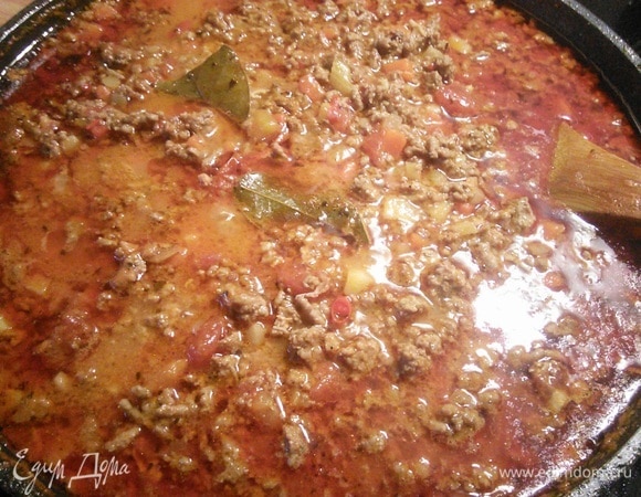 Добавить фарш и жарить около 3 минут. Добавить томатную пасту. Очистить чили, разрезать вдоль, вымыть и удалить семена. Разрезать стручок на мелкие кусочки. Добавить в фарш чили, лавровый лист, анис, палочку корицы, влить бульон или воду и выложить помидоры, предварительно их измельчив.