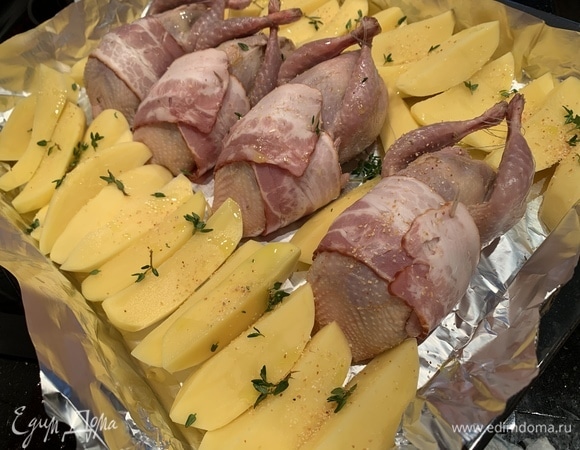 Картофель почистите и нарежьте дольками, выложите на противень вокруг перепелок. Посыпьте листиками тимьяна и чесноком. Сбрызните трюфельным маслом.