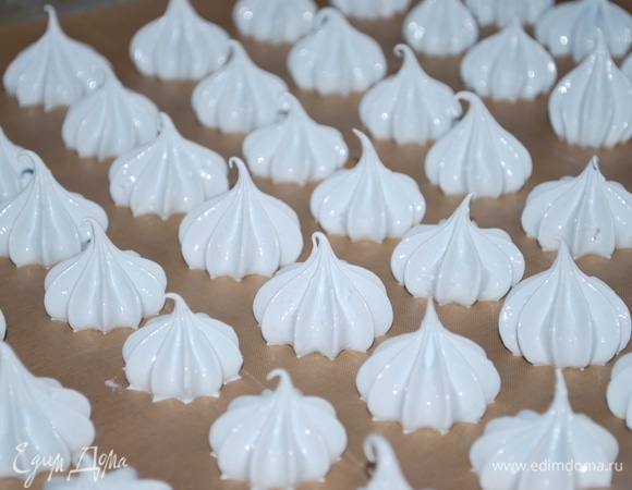 Переложите готовую белковую массу в кондитерский мешок с насадкой (я одну порцию подкрасила синим пищевым красителем, чтобы получился нежный голубой цвет). На противень выстелите пергамент и отсадите безе. Выпекайте в духовке при 90–100°C, режим «верх-низ».