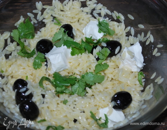 В макароны орзо добавьте кинзу, чайную ложку оливкового масла, маслины без косточек и кусочки творожного сыра.
