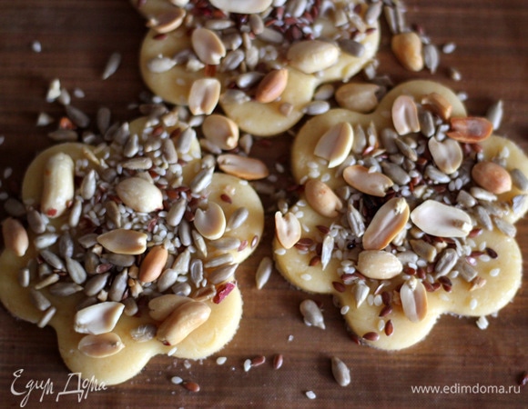 Любыми формочками вырезаем печенье. Смазываю белком для того, чтобы семечки прилипли к тесту и не ссыпались. И посыпаю семечковой смесью. Посыпку слегка придавить пальчиками.